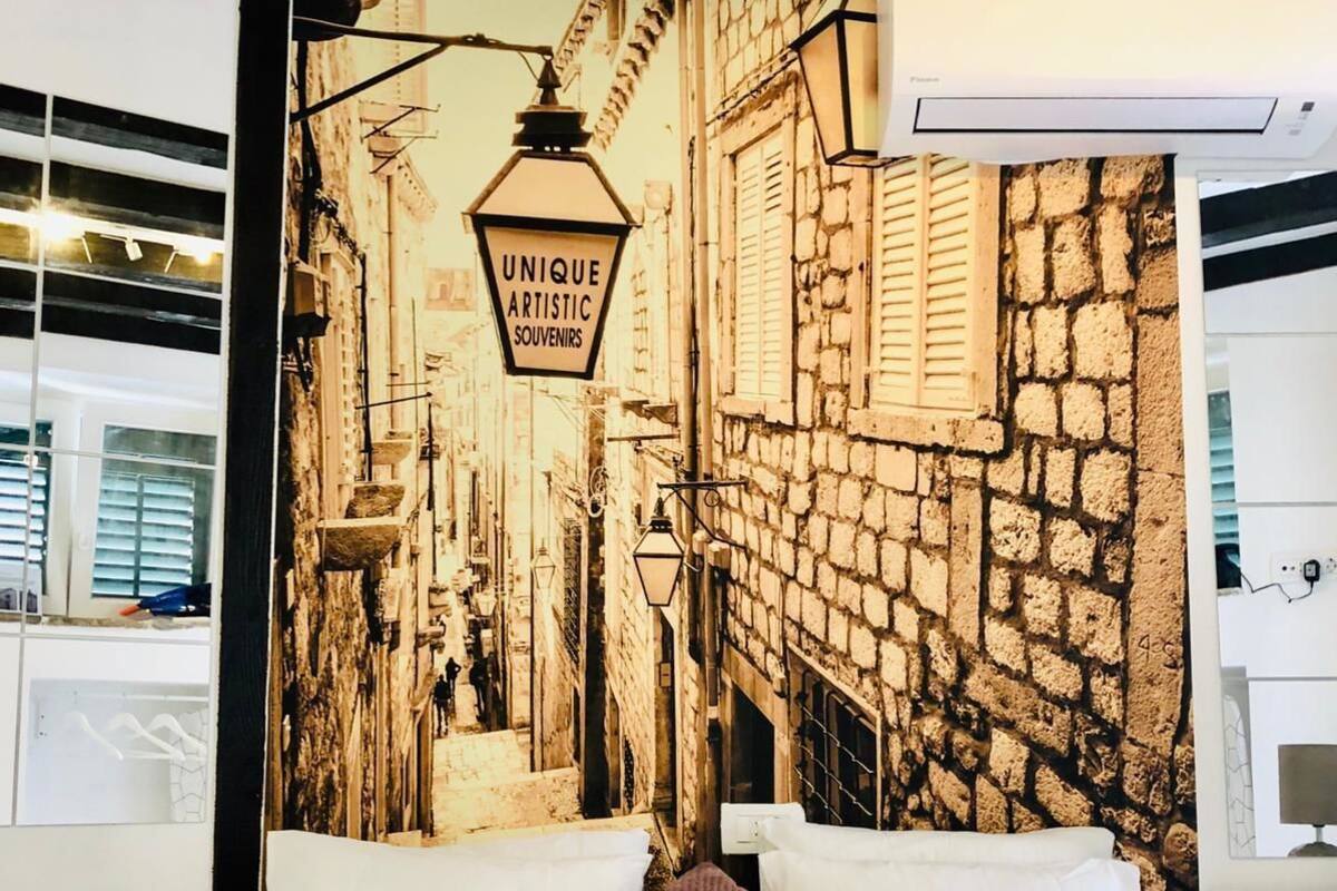 A hotel room with a bed, pillows, and a wall mural depicting a street scene.