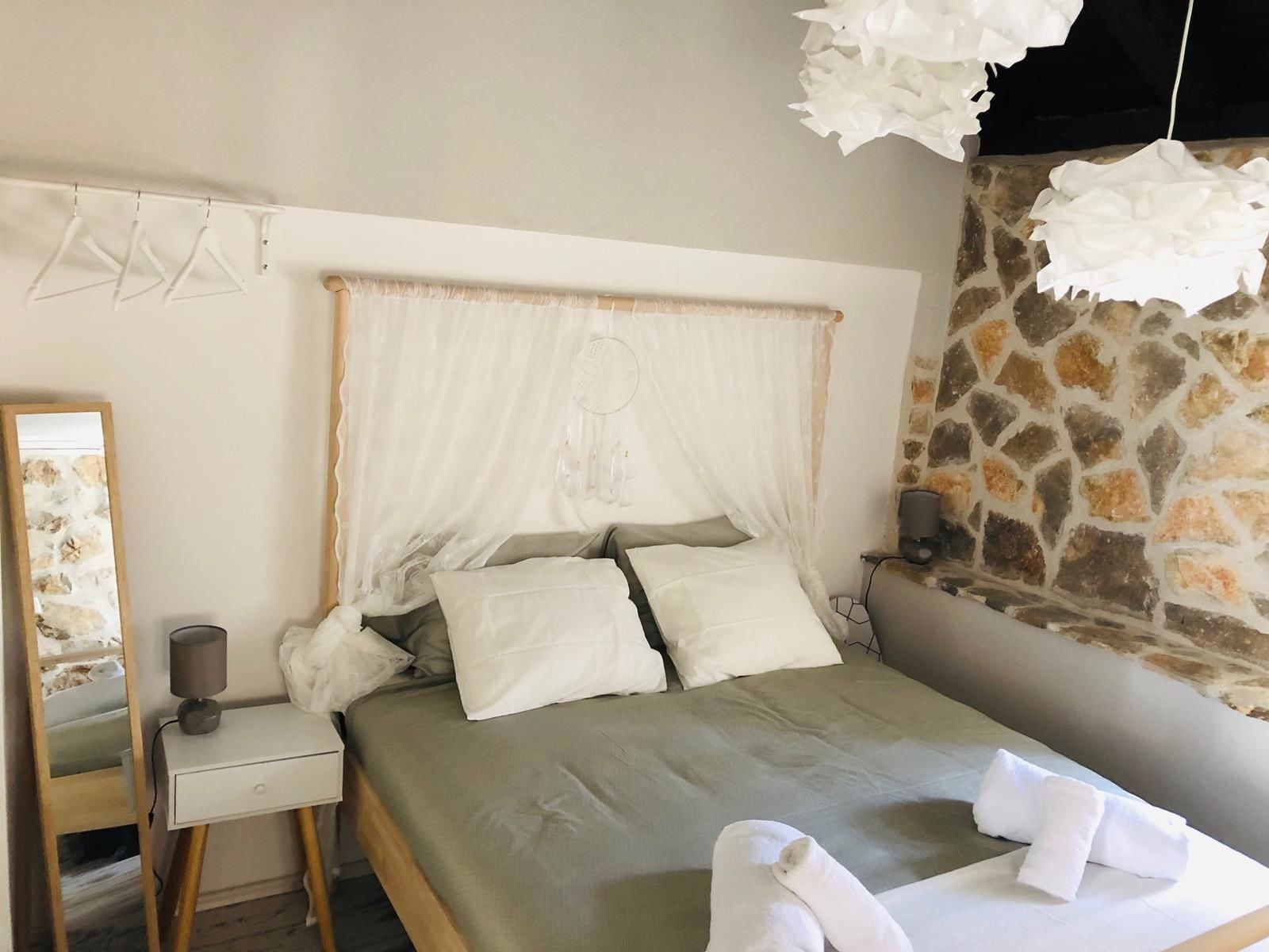 Una cama con dosel, una mesita de noche con lámpara y una pared de piedra.