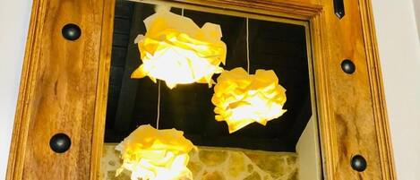 A mirror with a wooden frame and black knobs, reflecting three yellow lights.