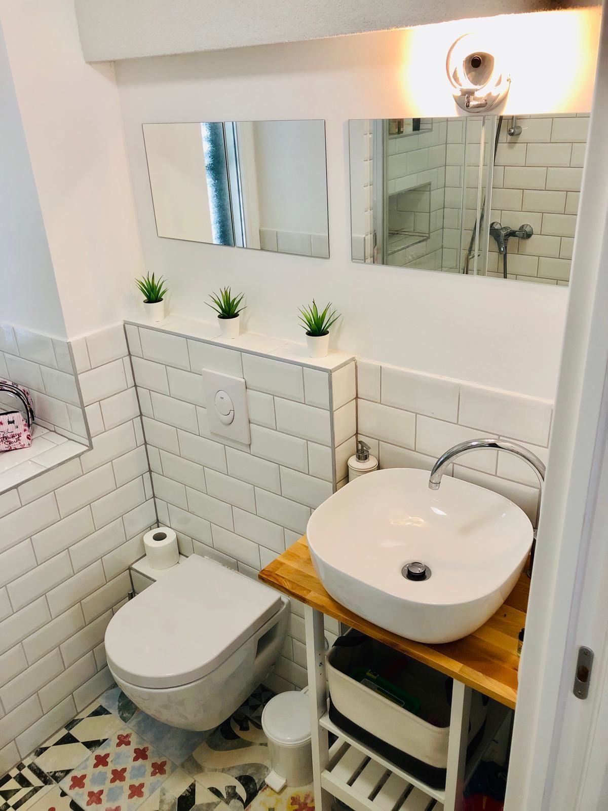 A compact bathroom with a white toilet, a sink with a wooden countertop, and a mirror above the sink.