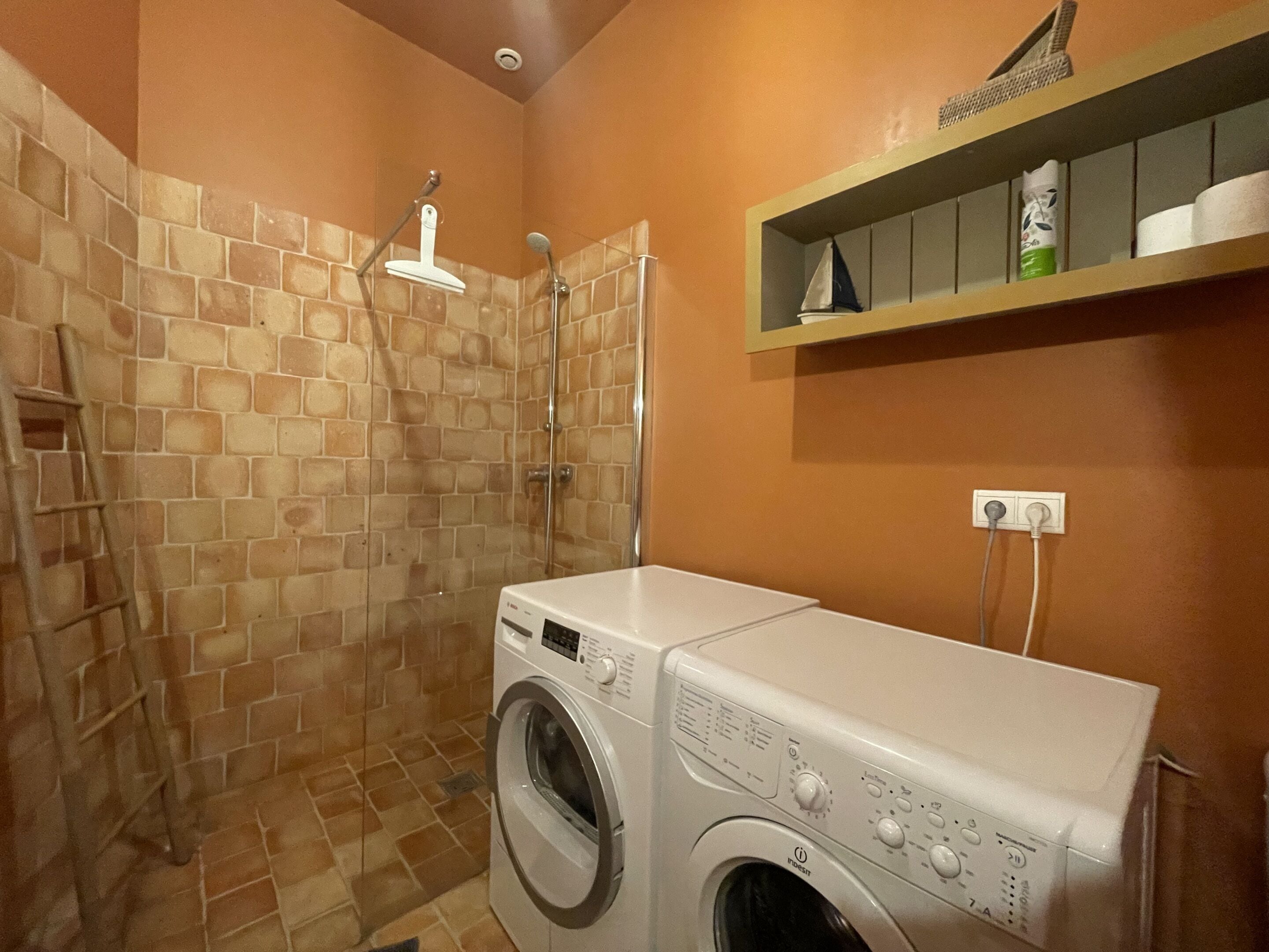 Una sala de lavandería con lavadora y ducha.