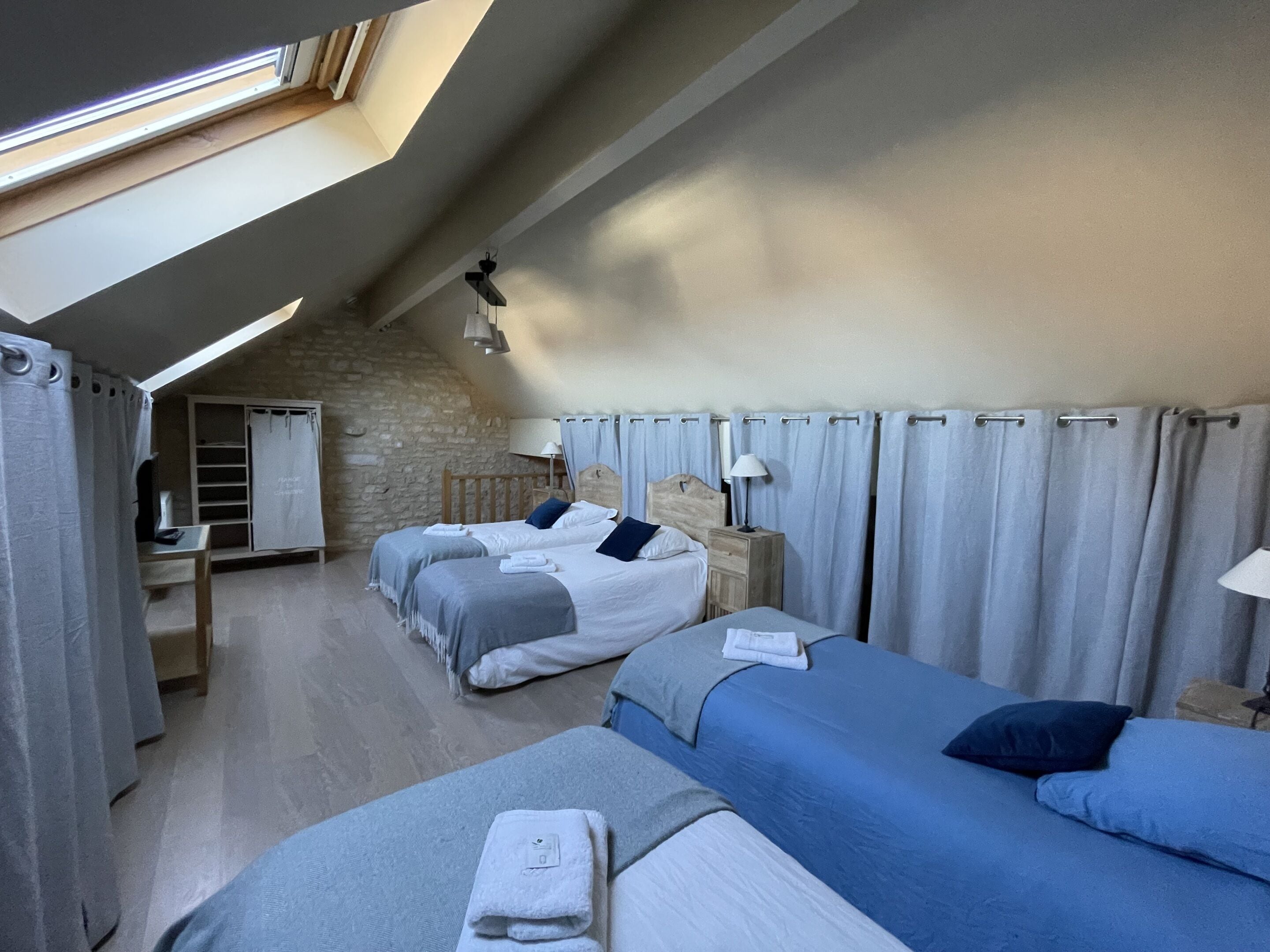 Un dormitorio con dos camas, un escritorio y una pared de piedra.