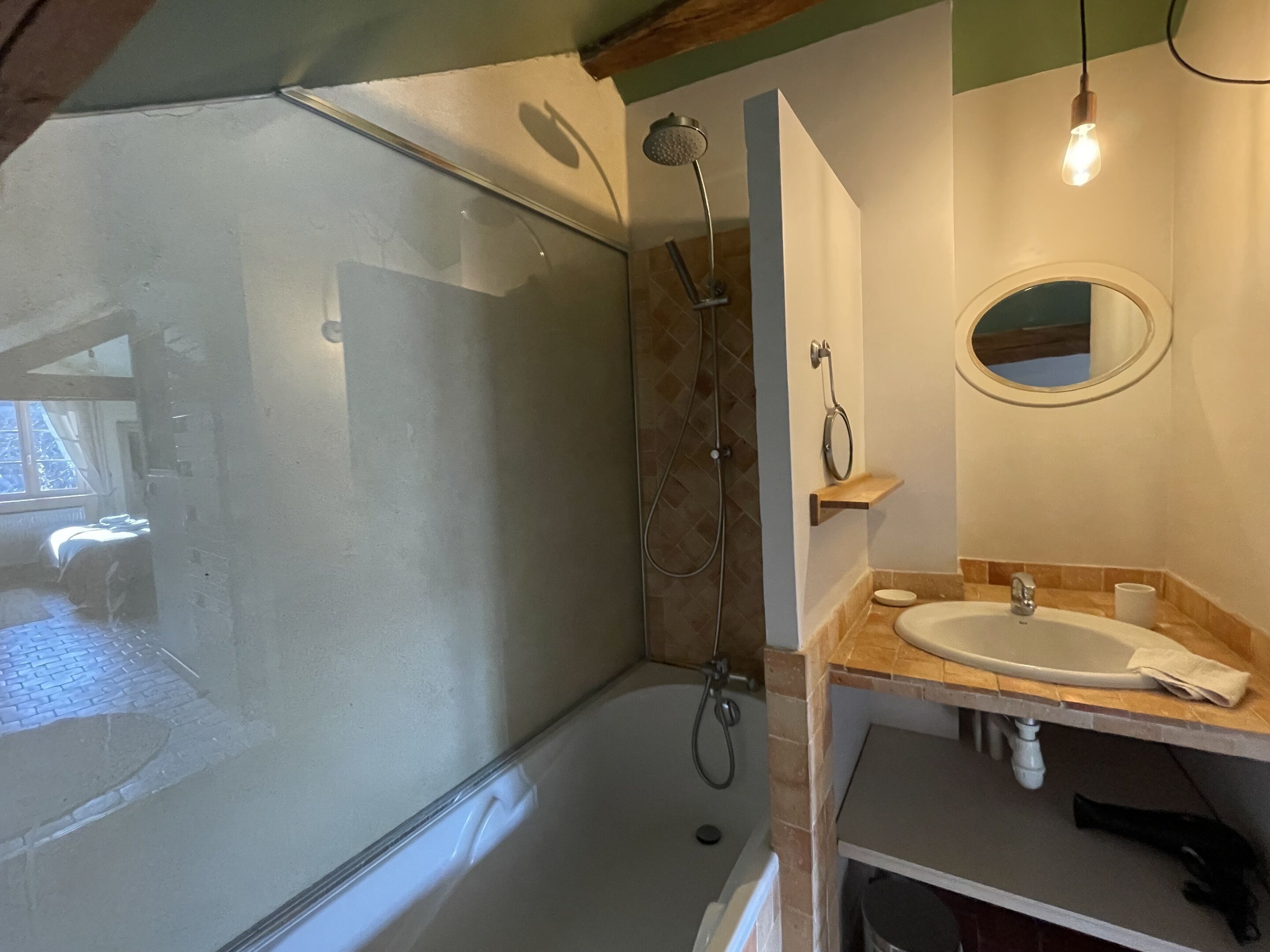Ein Badezimmer mit Duschkabine, Waschbecken, Spiegel und Handtuchhalter.