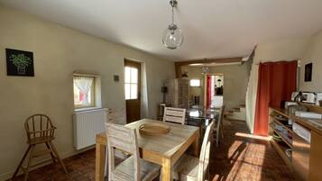 A spacious kitchen with a dining area, a radiator, and a window with curtains.