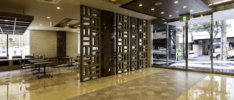 A spacious lobby with a polished floor, seating area, and a view through large glass doors.