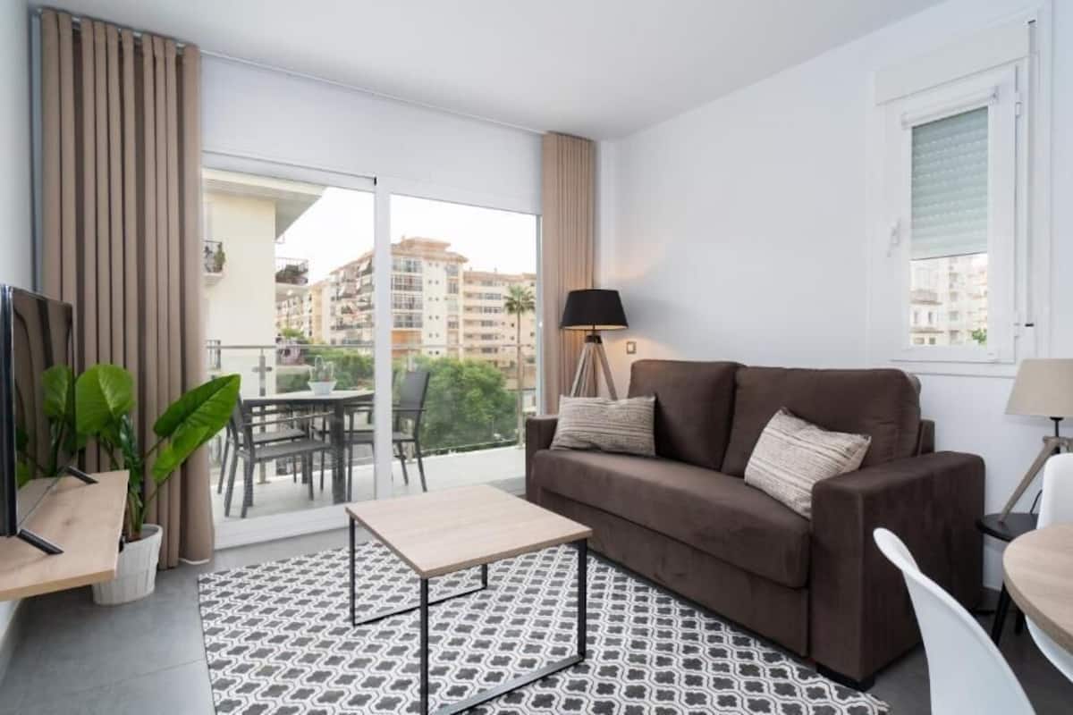 A modern living room with a sofa, coffee table, and a dining area with a table and chairs.