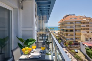 A balcony with a dining setup, including plates, glasses, and a vase with flowers. - Sur Suites La Dorada (Fuengirola)
