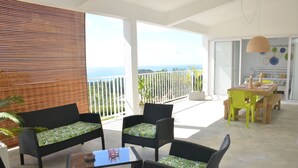 A balcony with wicker furniture, a table, and a view of the ocean. - Villa Zourit Rodrigues Bungalow (Rodrigues Island)