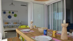 A dining area with a wooden table set for two, a wicker basket, and a can of beer. - Villa Zourit Rodrigues Bungalow (Rodrigues Island)