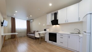 A modern kitchen with white cabinets, a built-in oven, and a white countertop.