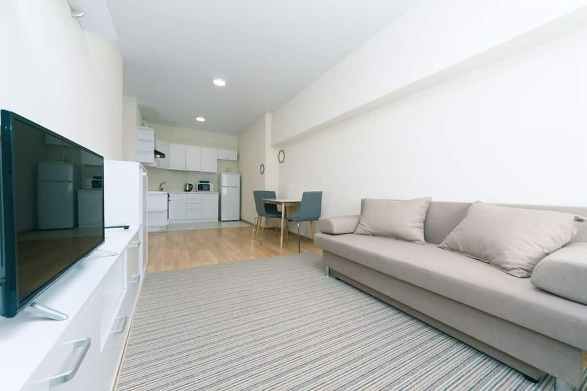 A modern apartment with a living room, a dining area, and a kitchen.