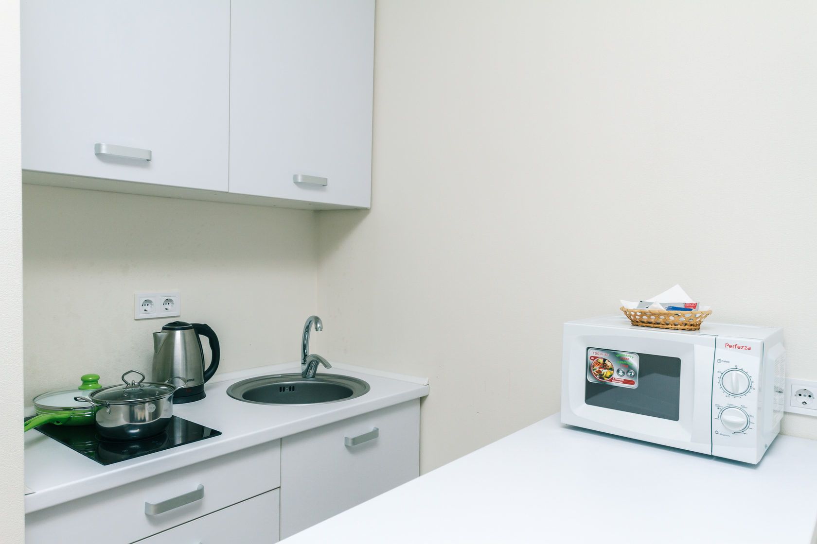 A small kitchenette with a sink, stove, and microwave.