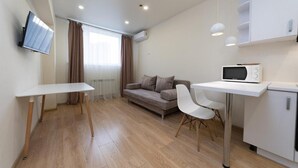 A modern, well-lit room with a sofa, a dining table, and a microwave.