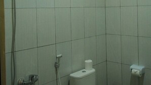A small bathroom with a toilet, a shower, and a window. - Ayuna Family Ubud (Ubud)