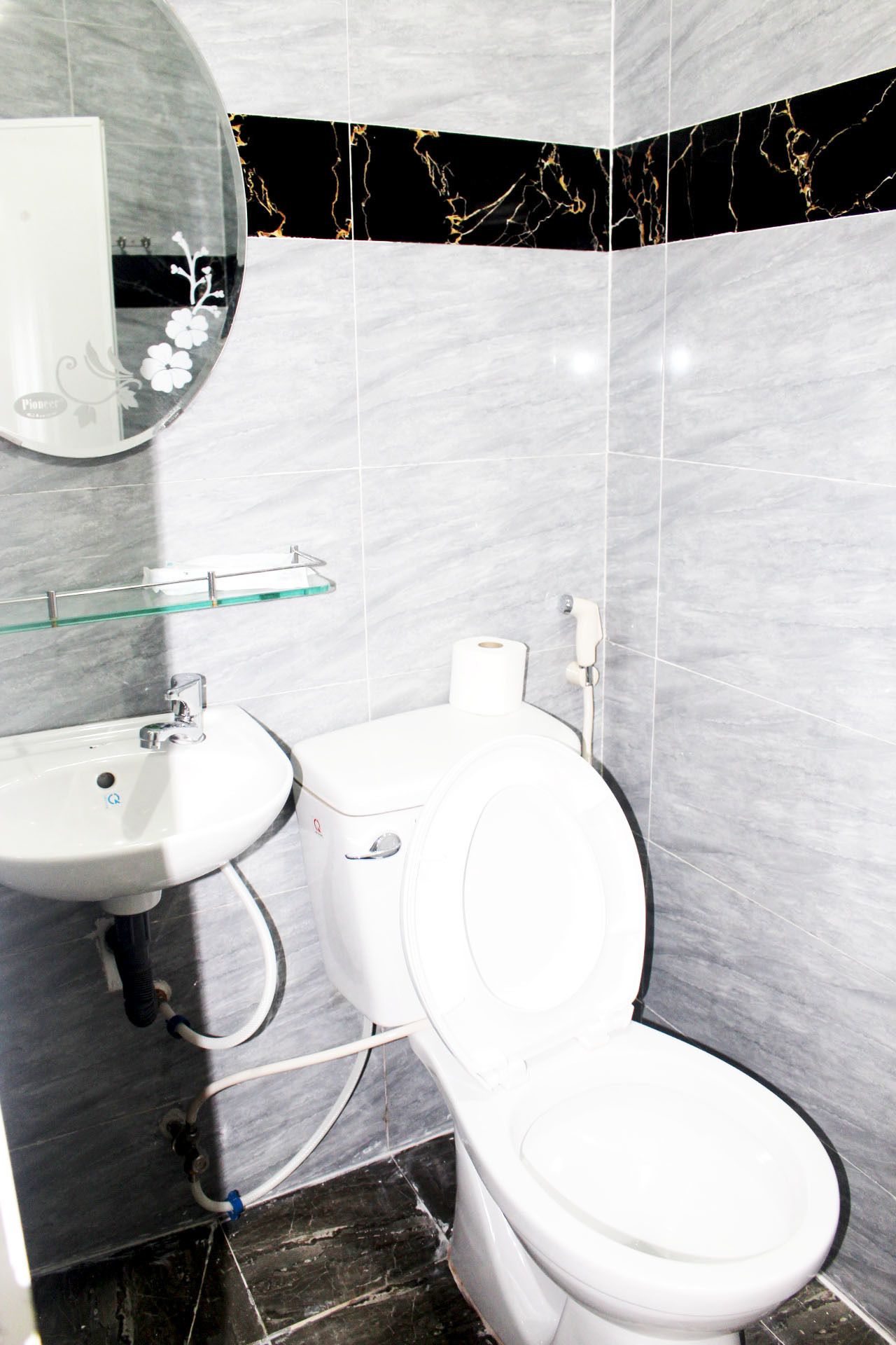 A bathroom with a white toilet, a sink, and a glass shelf.