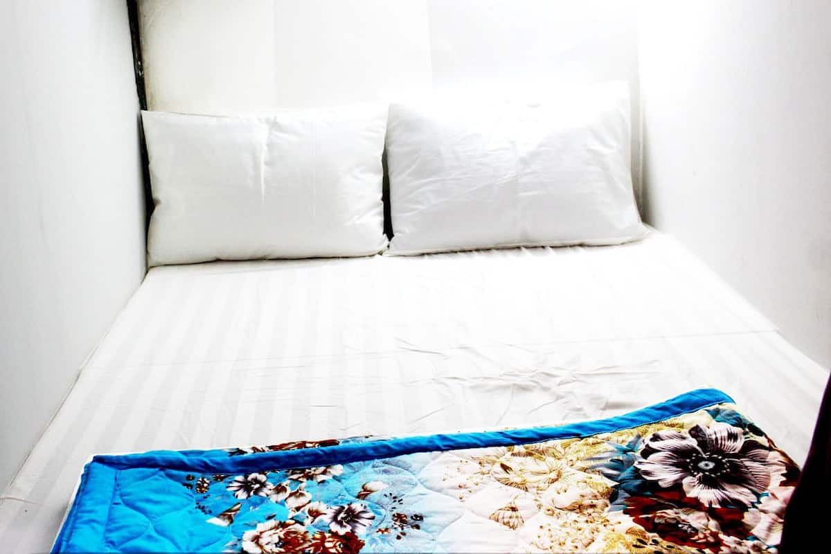 A bed with white linens and a floral-patterned blanket.