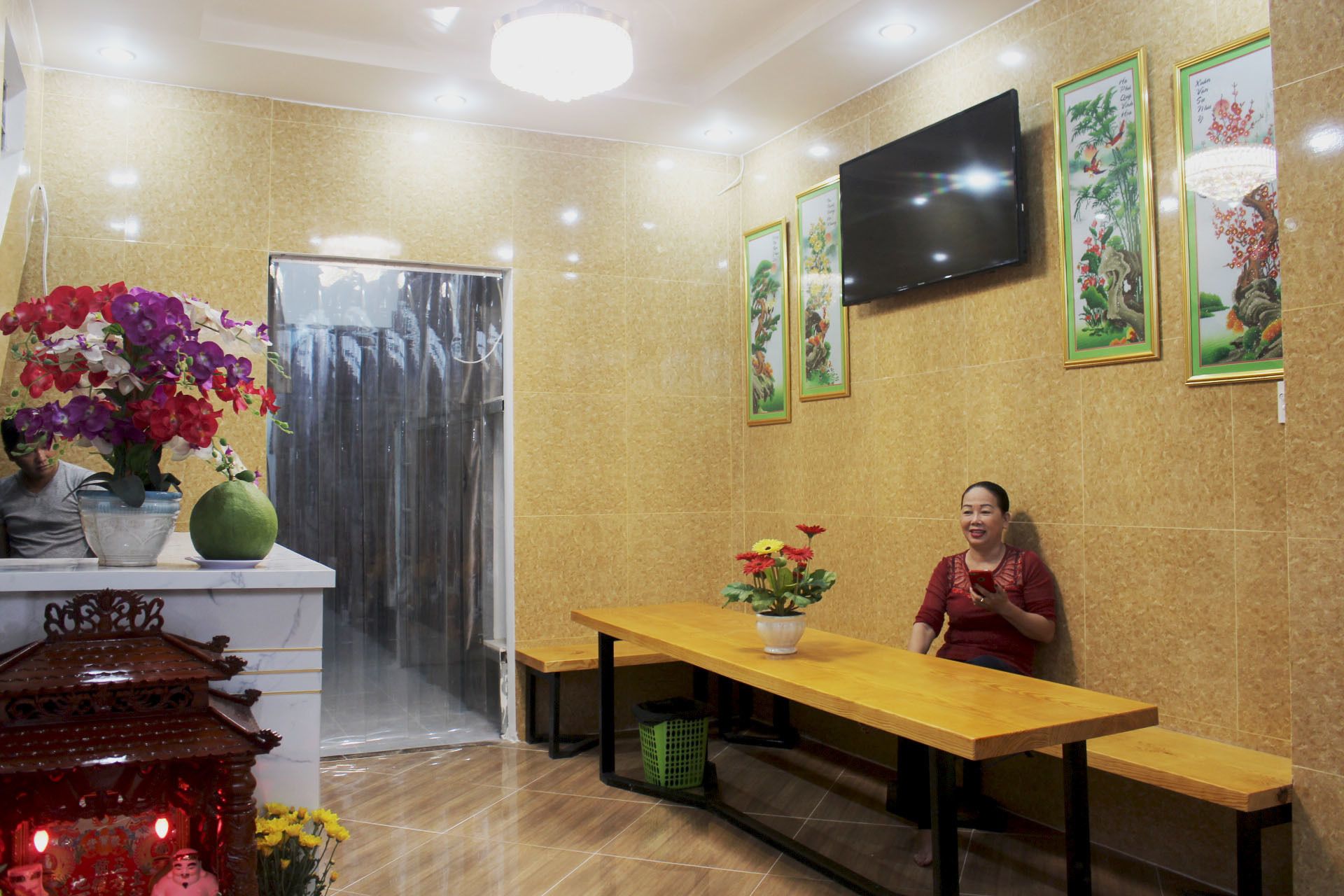 A reception area with a wooden reception desk, a TV mounted on the wall, and framed artwork on the walls.