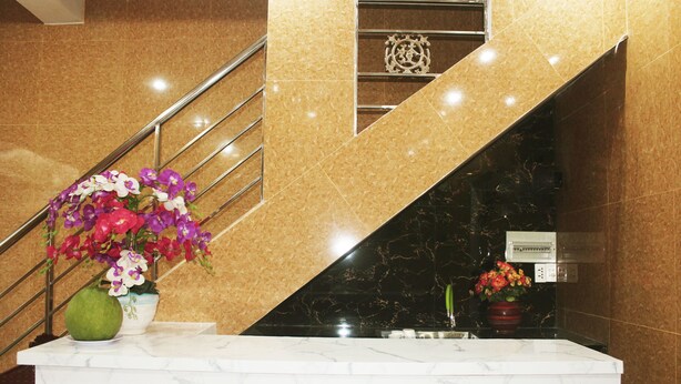 A marble reception desk with a handrail and a flower arrangement. - Saigon City Center - Hostel (Ho Chi Minh City)