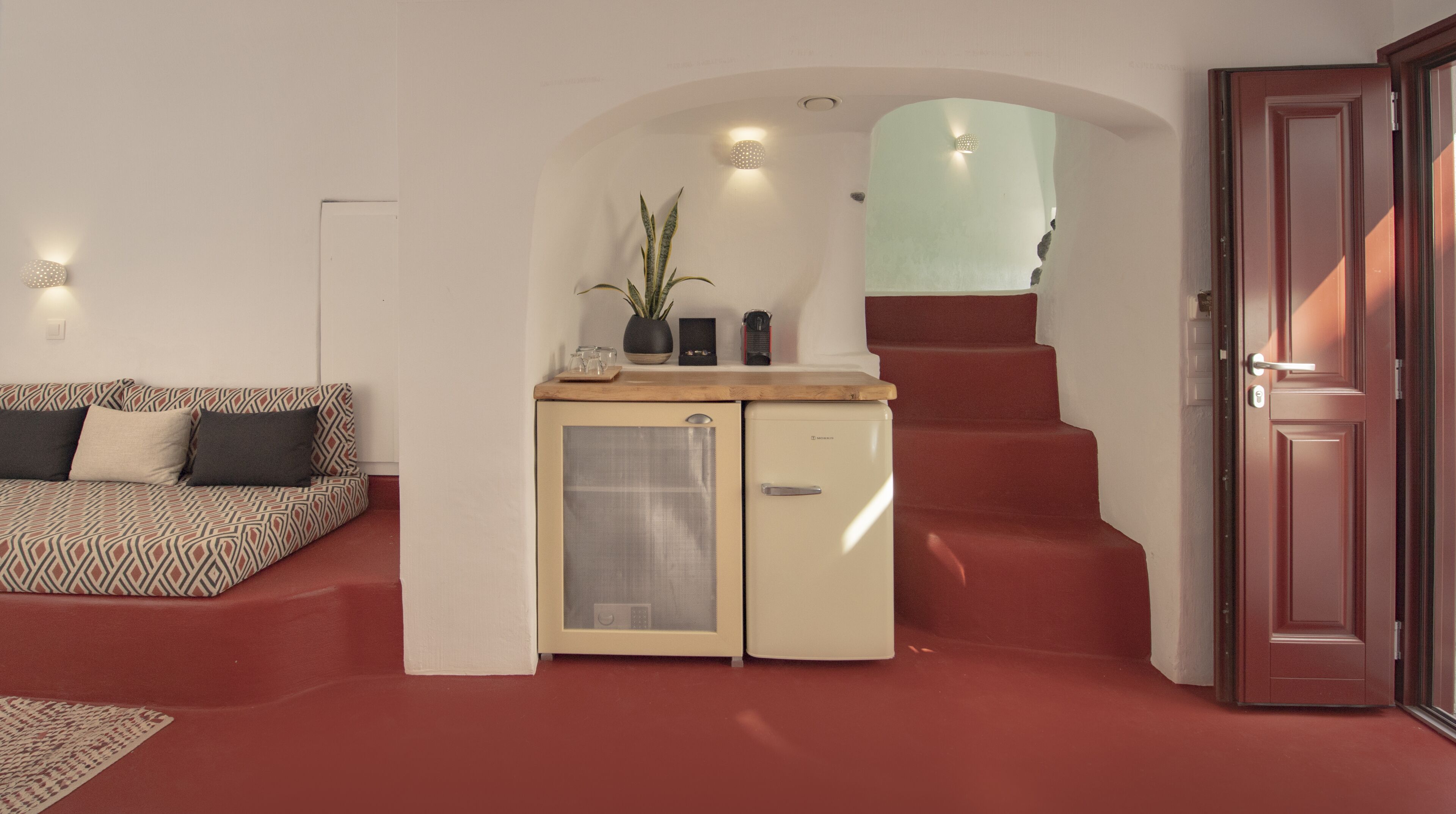 Un espace de vie compact comprenant un canapé, une kitchenette et un escalier.