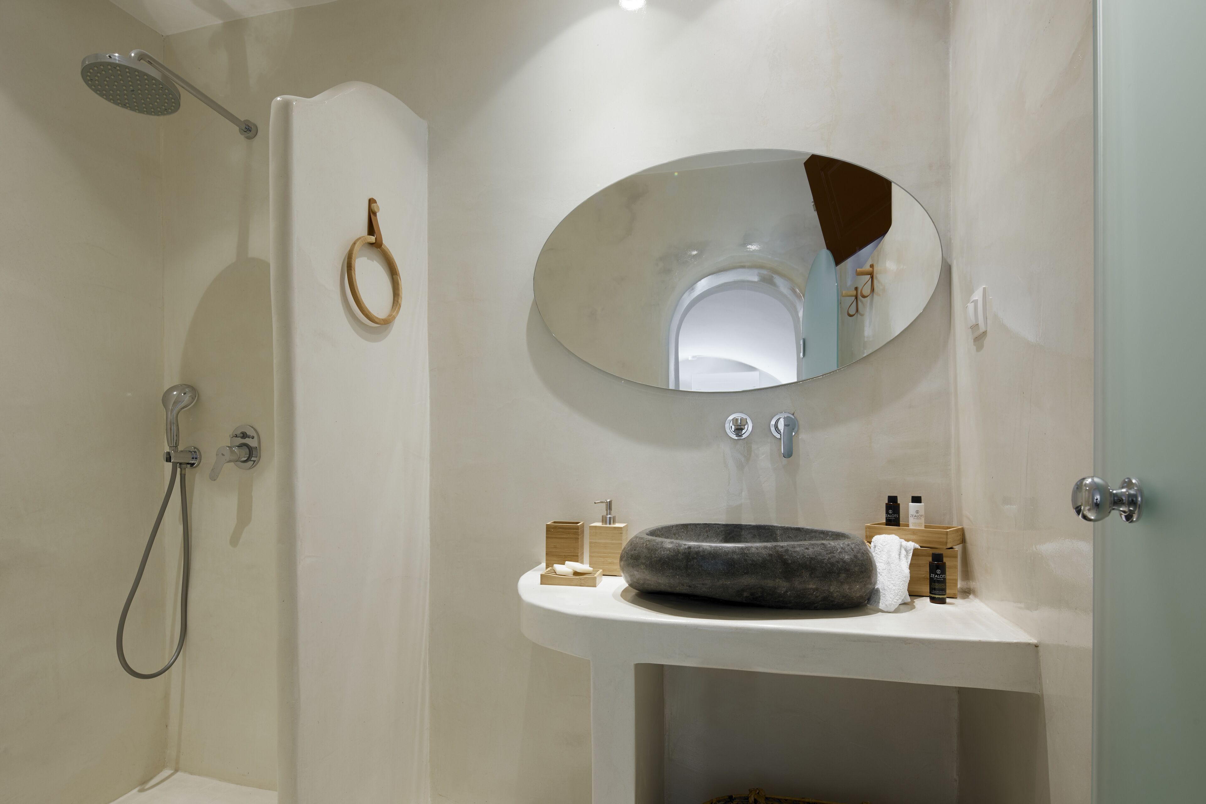 A bathroom with a shower, a sink with a mirror, and toiletries on the countertop.