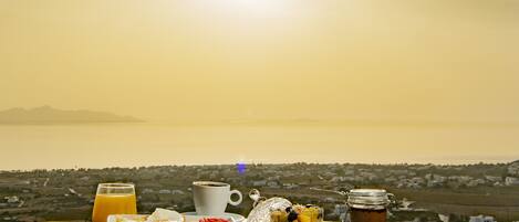Ein Frühstückstisch mit Toast, Eiern und einem Glas Orangensaft, vor einer malerischen Küstenlandschaft.
