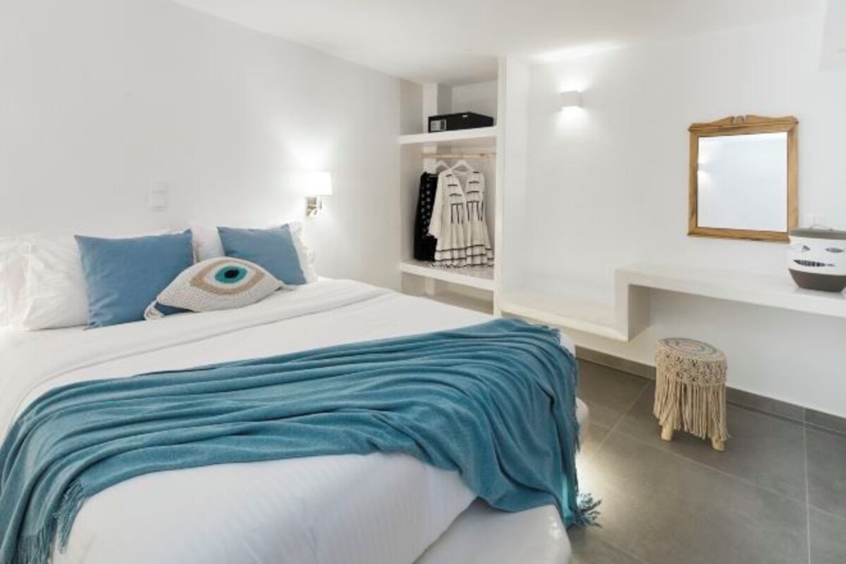 Una camera da letto con un letto, un armadio, uno specchio e un tavolino rotondo.