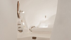 Un baño moderno con una bañera, ducha y lavamanos. Hay rocas colocadas en el suelo cerca de la bañera.