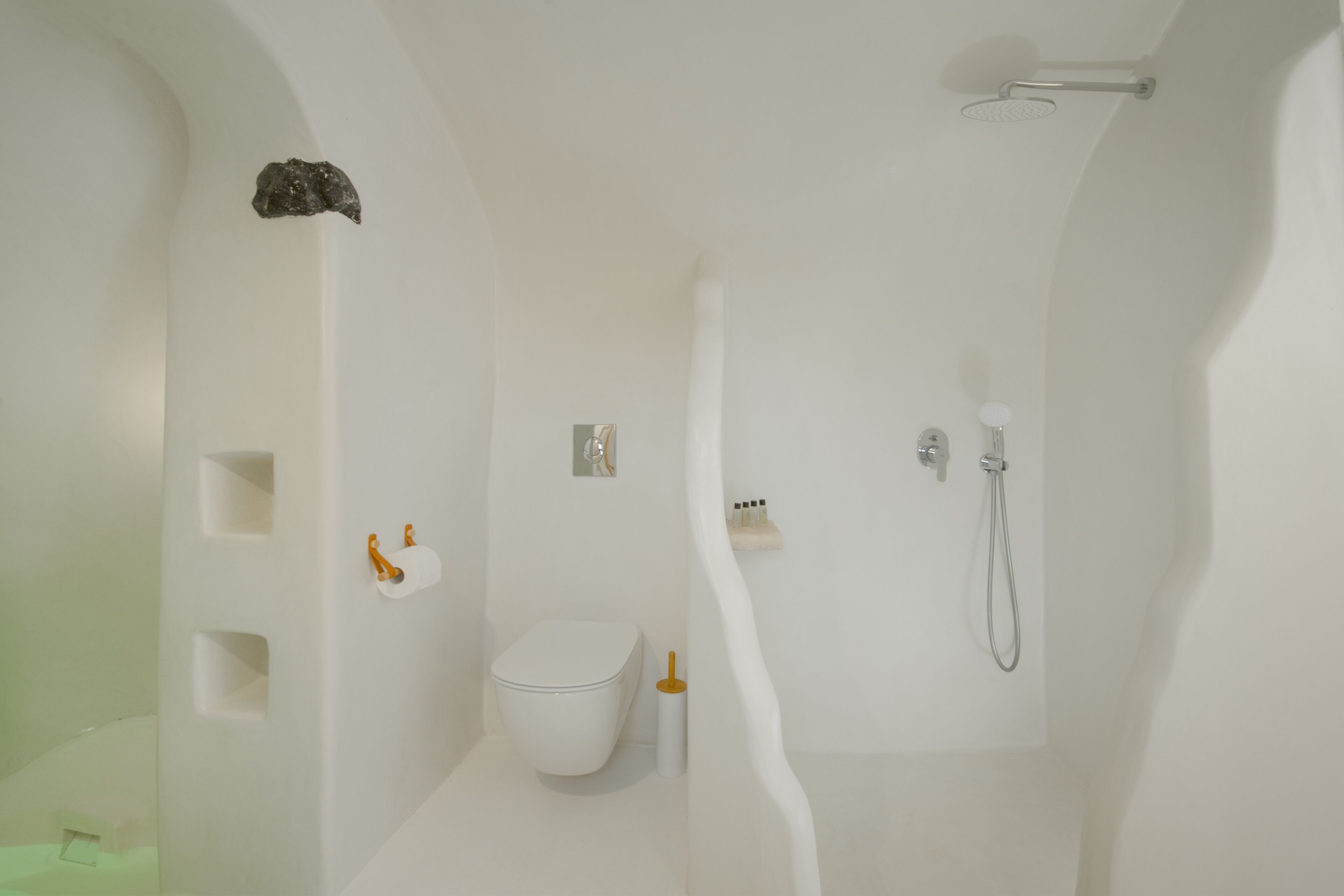 A modern bathroom with a white toilet, a shower, and a sink.