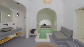 Ein modernes Badezimmer mit einem großen Spiegel, einem Waschbecken, einer Holzablage, einer grünen Matte und einem grauen Sofa.