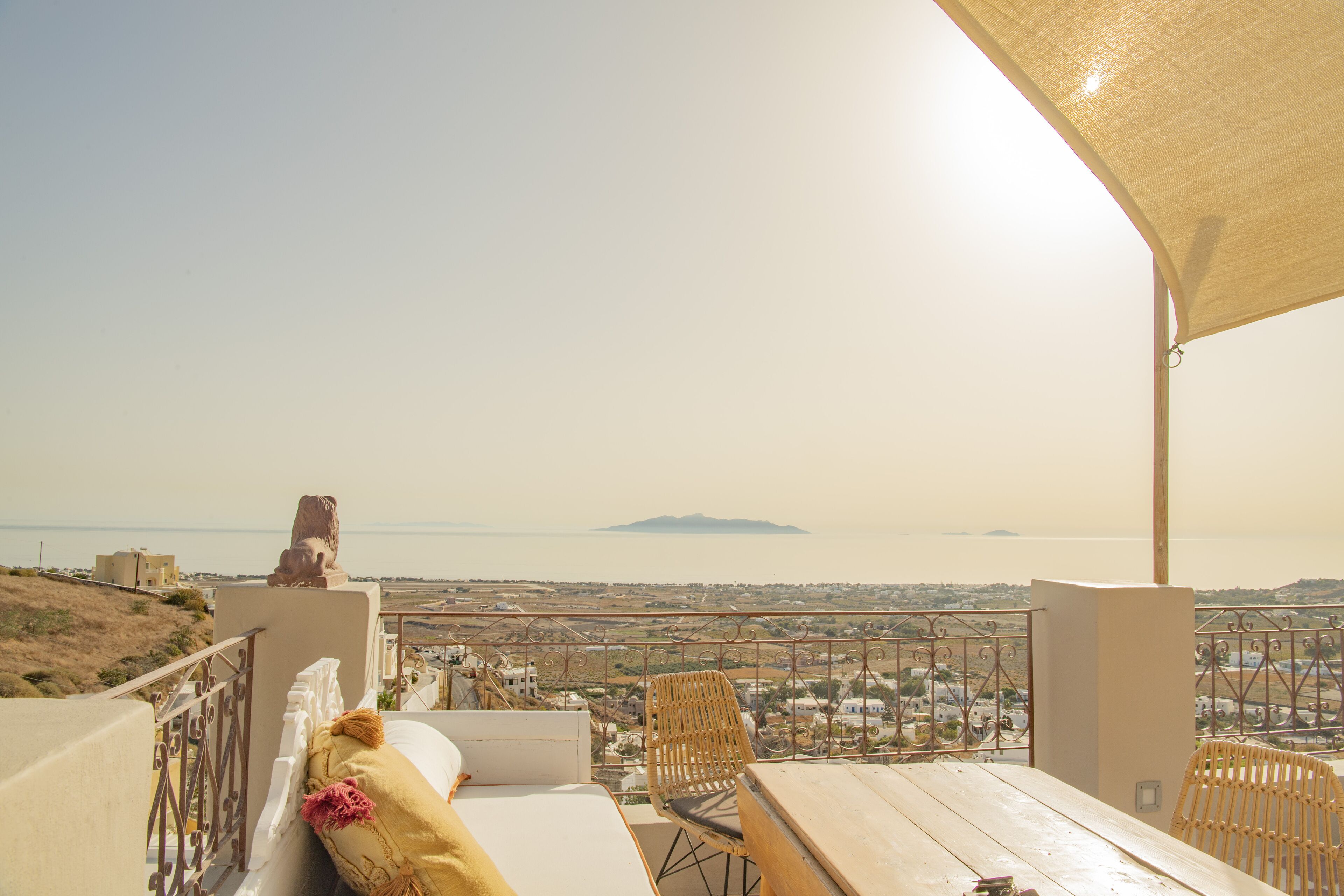 Une terrasse offrant une vue sur la mer et les montagnes lointaines, aménagée avec une table et des chaises.