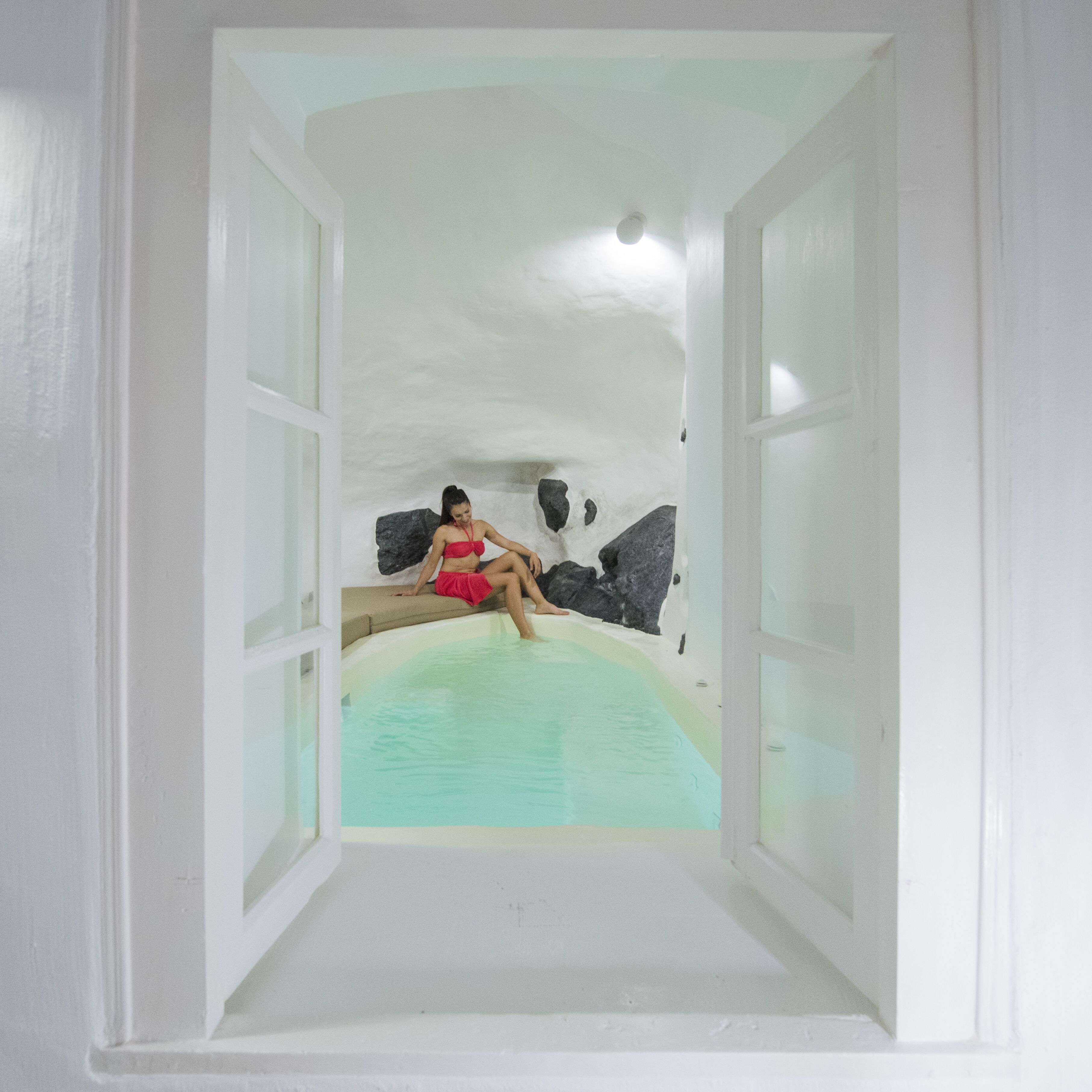 A woman sitting in a bathtub with a view of a cave-like interior.