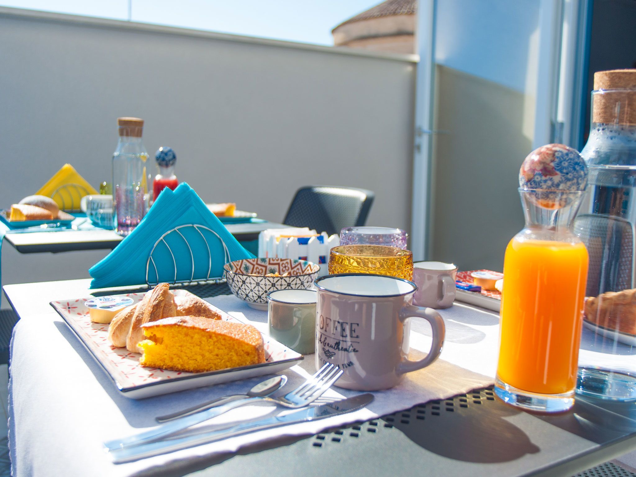 A breakfast table with a plate of food, a coffee mug, a glass of orange juice, and various breakfast items.