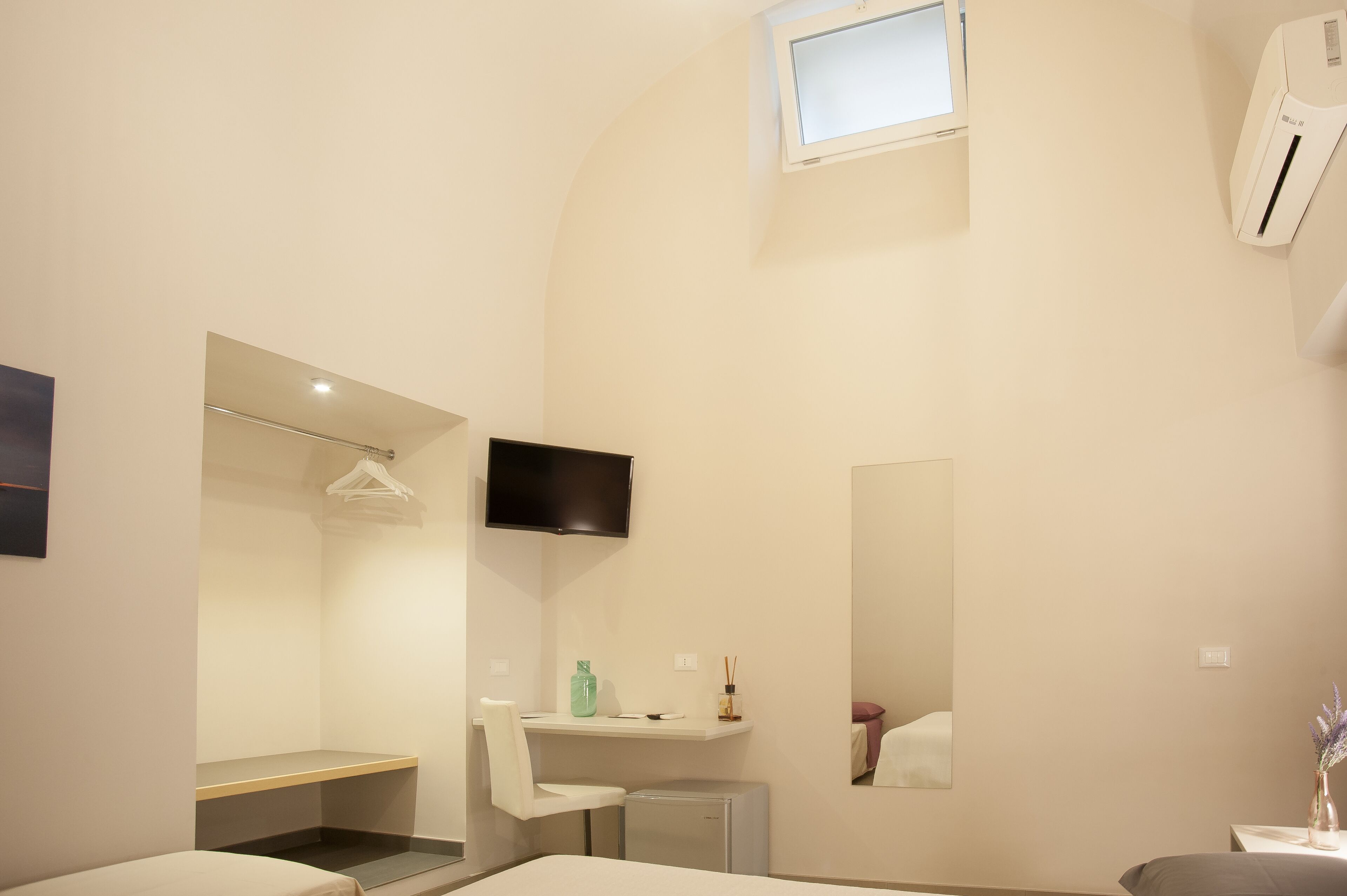 Ein modernes Badezimmer mit Dusche, Waschbecken, Spiegel und einem an der Wand befestigten Fernseher.