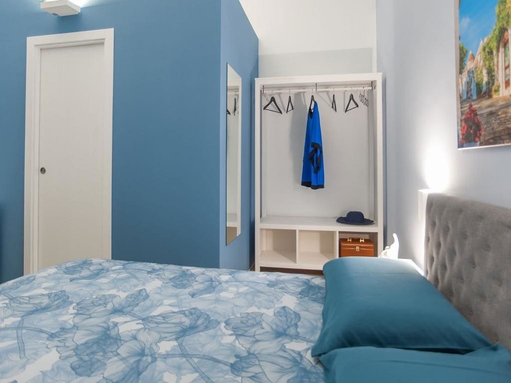 A bedroom with a bed, a wardrobe, and a painting on the wall.