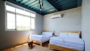 A room with two wooden beds, a window with blinds, a ceiling fan, and an air conditioning unit. - Liuqiu Backpackers Hostel (Liuqiu)