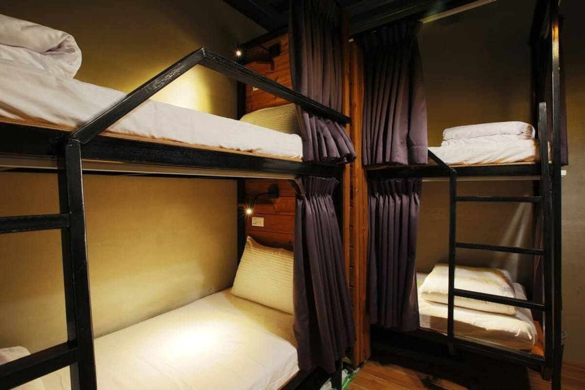 A bunk bed room with wooden railings and curtains.