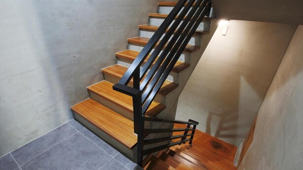A staircase with wooden steps and a black metal railing. - Liuqiu Backpackers Hostel (Liuqiu)