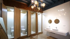 A modern bathroom with wooden doors, a chandelier, and a marble wall. - Liuqiu Backpackers Hostel (Liuqiu)