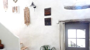 A staircase leading to a room with a door, a wall-mounted light fixture, and a potted plant.