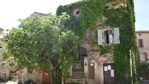 A historic building with ivy-covered walls, a wooden door, and a plaque.