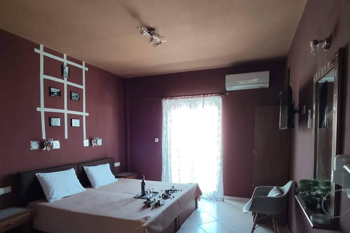 Quarto com cama, escrivaninha, cadeira, decoração de parede em formato de escada e janela com cortinas.