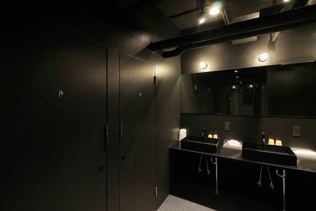 Une salle de bain moderne avec des meubles de couleur sombre, un grand miroir et deux vasques dotées d’un éclairage sous le plan.