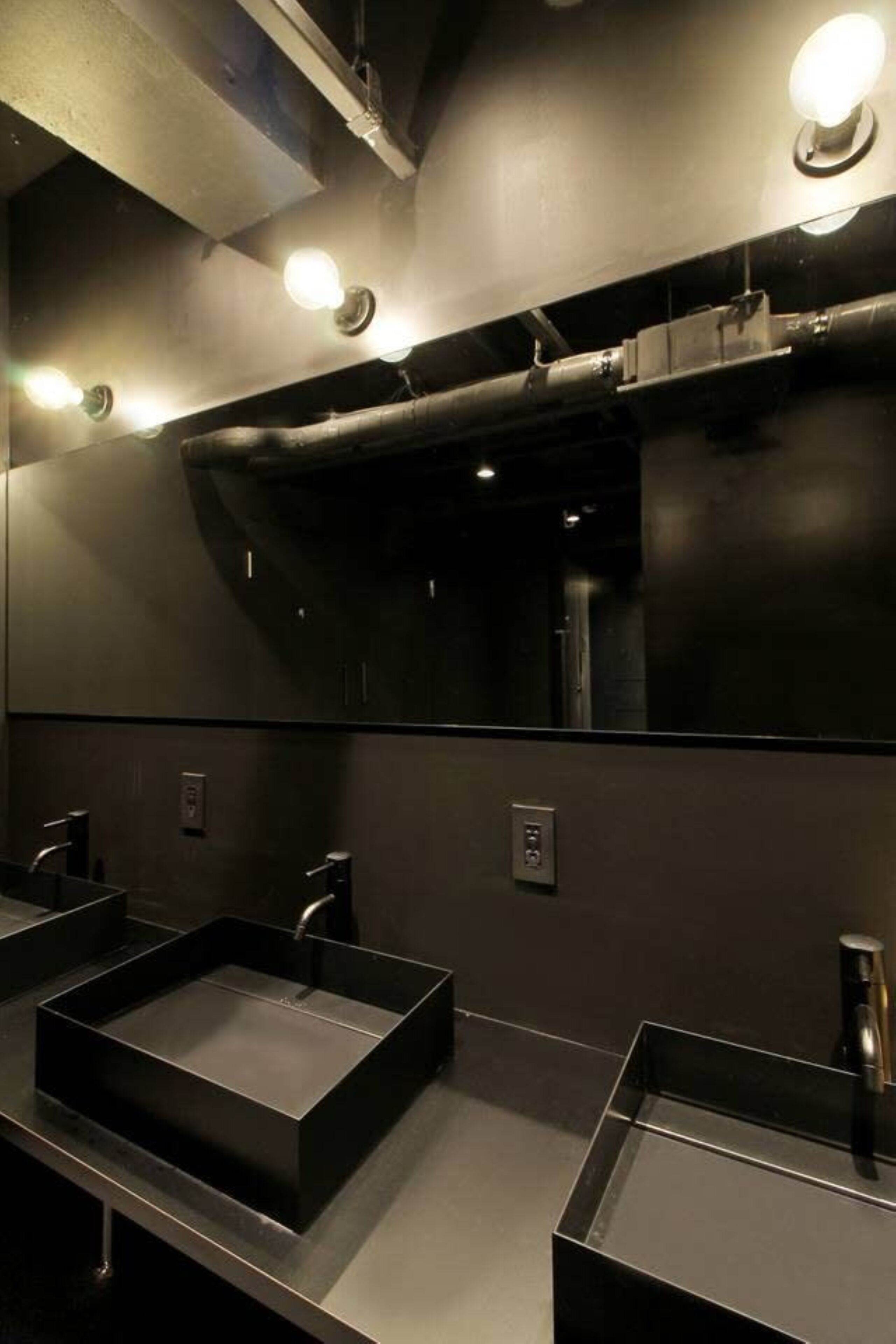Un baño moderno con dos lavamanos, un espejo grande e iluminación en el techo.