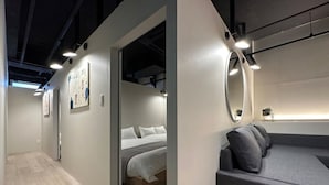 Moderni hotellihuone, jossa on sänky, sohva ja suuri peili.