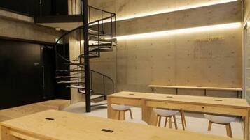 A modern kitchen with a spiral staircase, wooden tables, and white stools.