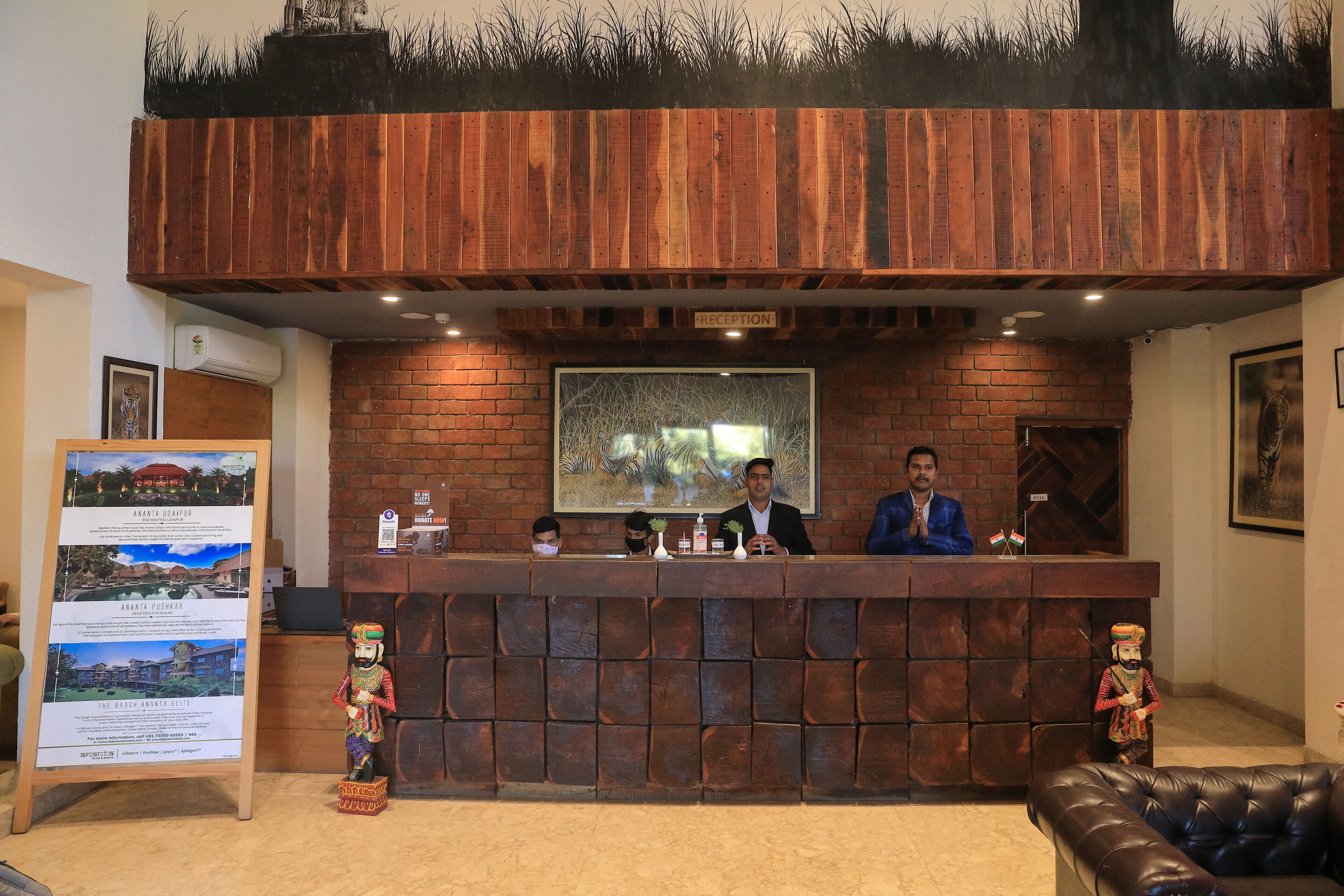 A reception desk with a brick wall backdrop, a framed picture above the desk, and a signboard to the left.