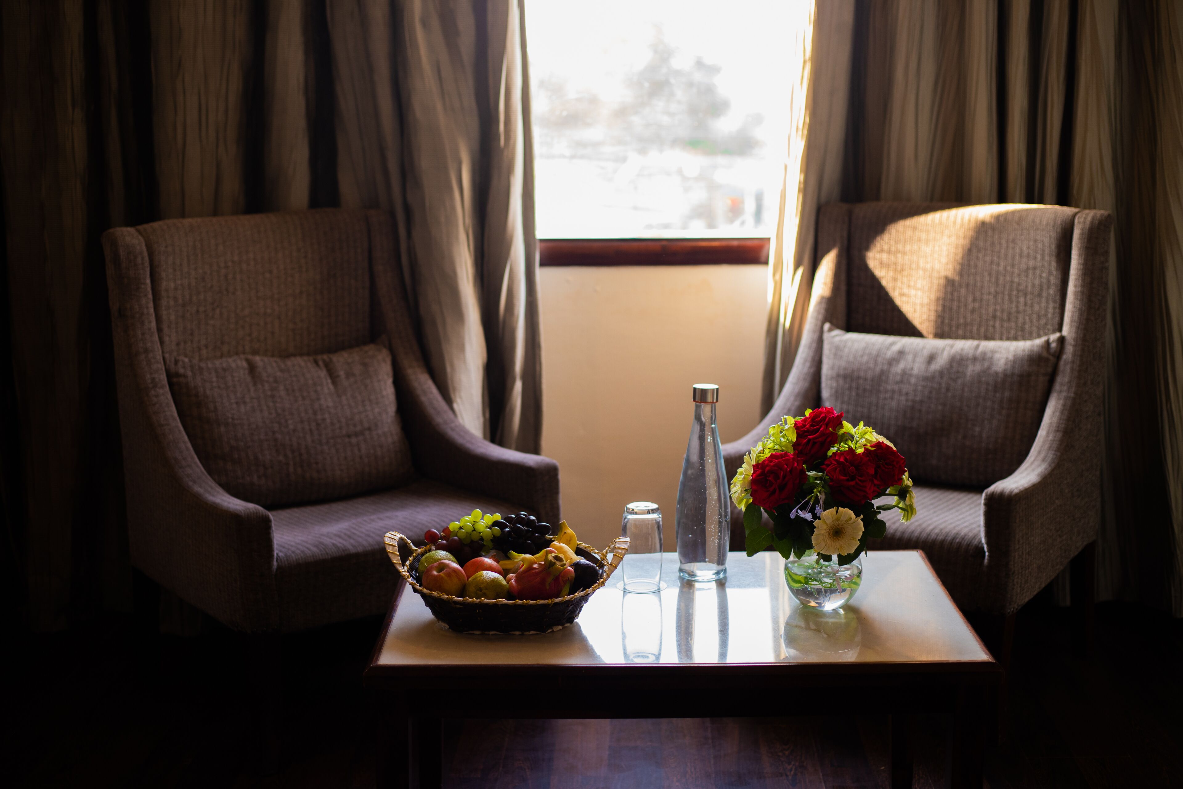 Dos sillones, una mesa con frutero, un florero y salero y pimentero.