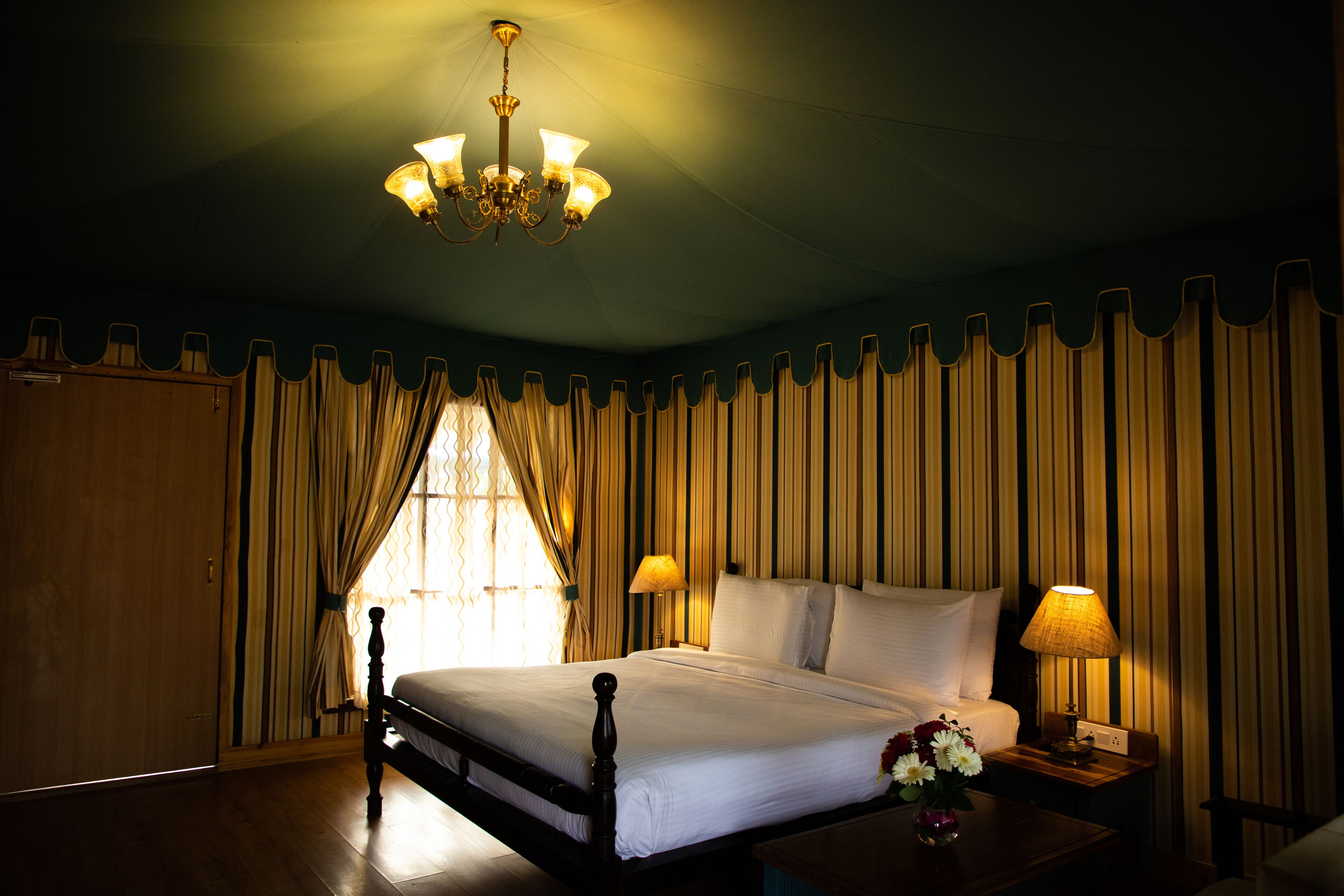 A neatly made bed with white linens, a wooden headboard, and a nightstand with a lamp.