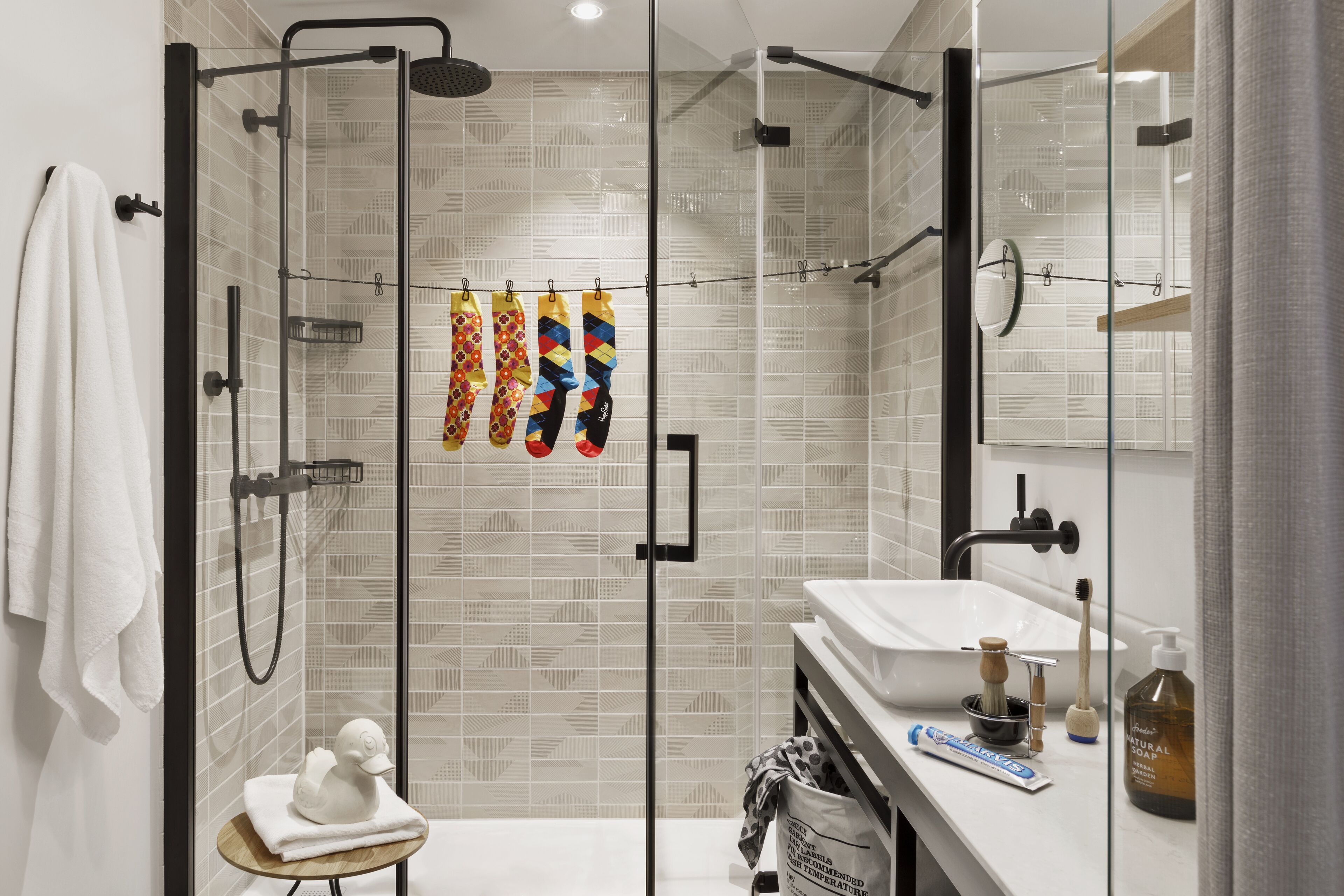 A modern bathroom with a glass-enclosed shower, a white sink, and a mirror.