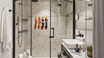 A modern bathroom with a glass-enclosed shower, a white sink, and a mirror.
